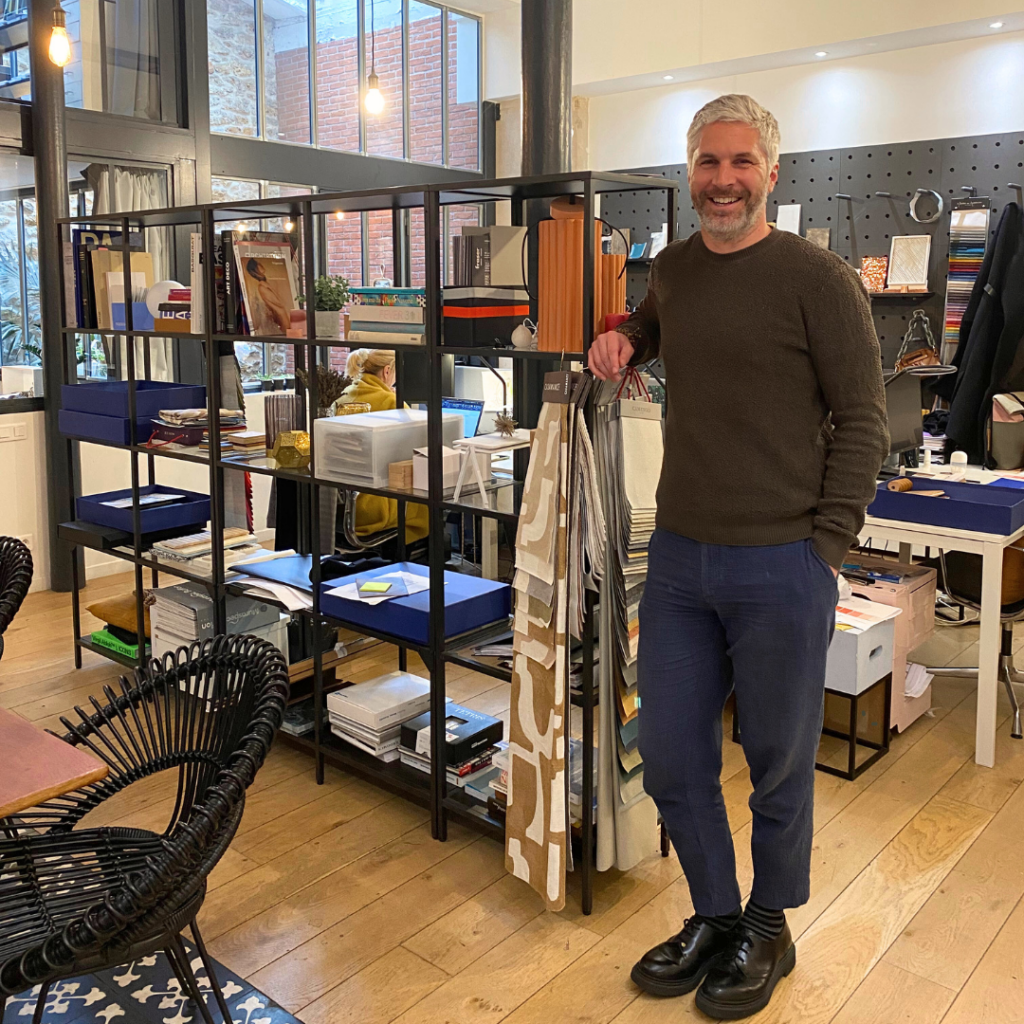 Michaël Malapert dans son agence de design au style industriel avec verrière, briques rouges et bibliothèque de matériaux.