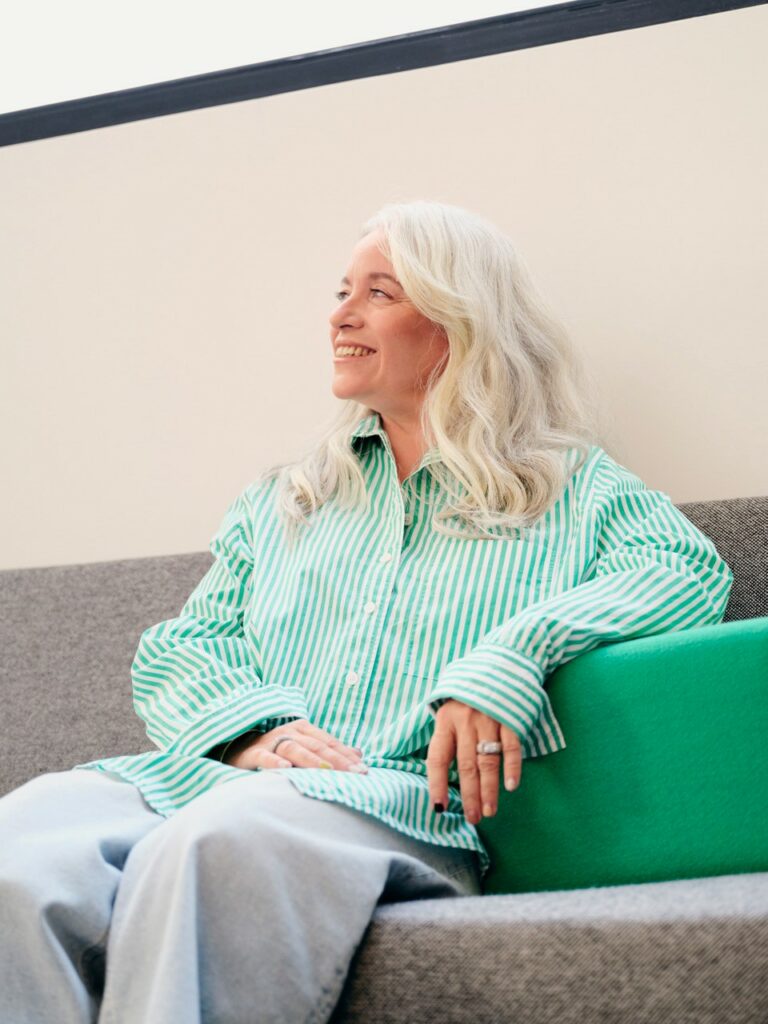 Portrait d'Anne-Sophie Prevot, femme élégante aux chevaux blancs et portant une chemise verte rayée.